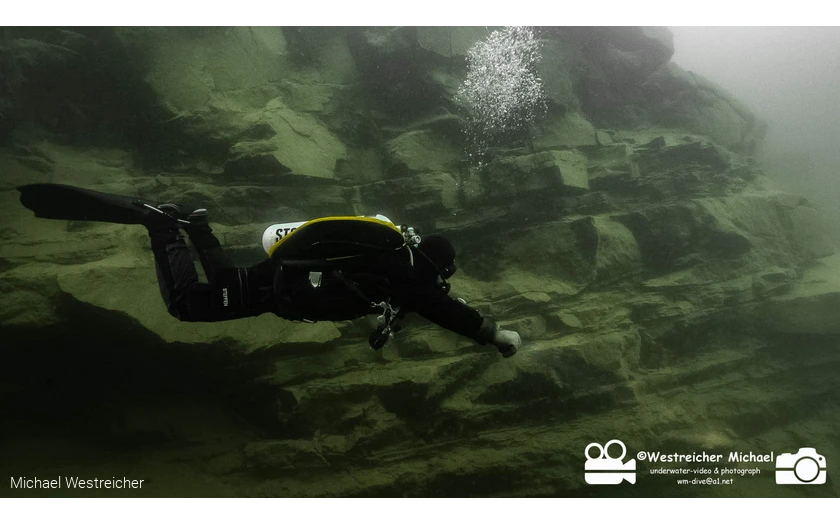 Tauchende Person schwimmt über Felsen auf dem Seegrund.