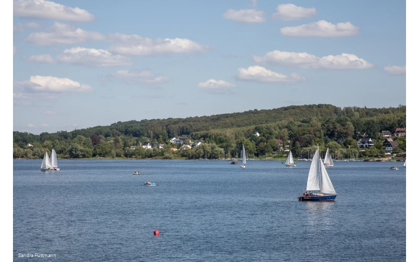 Segelboot auf dem ruhigen Möhnesee unter blauem Himmel mit Wolken.