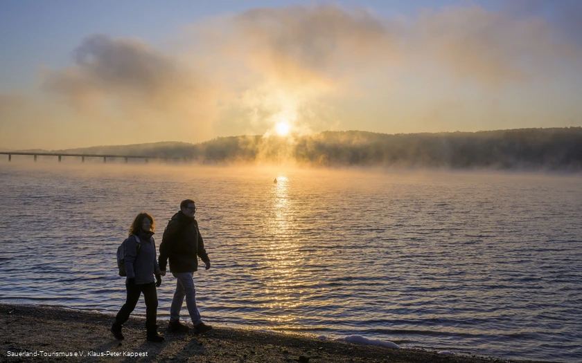 Wanderer am Möhnesee bei Sonnenaufgang