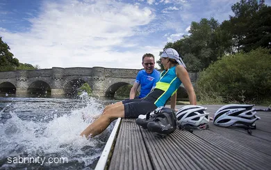 Radfahrende plantschen mit Füßen im Wasser