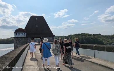 Gruppe von Personen spaziert über die Staumauer des Möhnesees.
