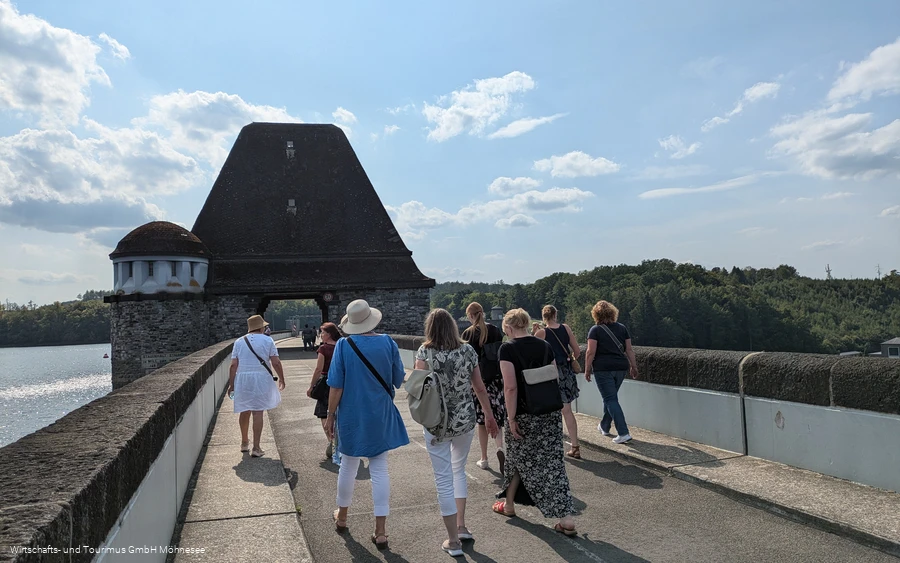 Gruppe von Personen spaziert über die Staumauer des Möhnesees.