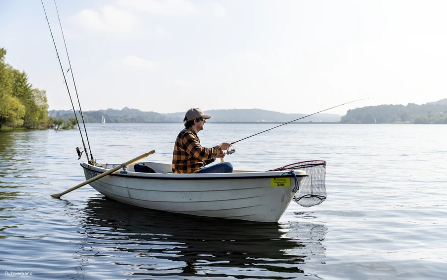 Person angelt von einem kleinen Ruderboot auf dem Möhnesee.