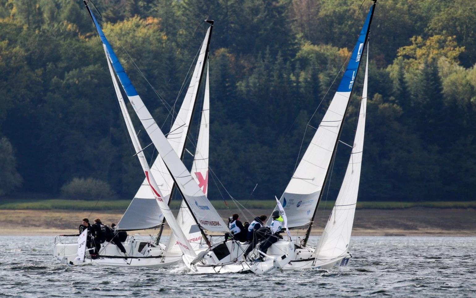 Drei Segelboote mit Seglern und Seglerinnen auf dem Möhnesee.