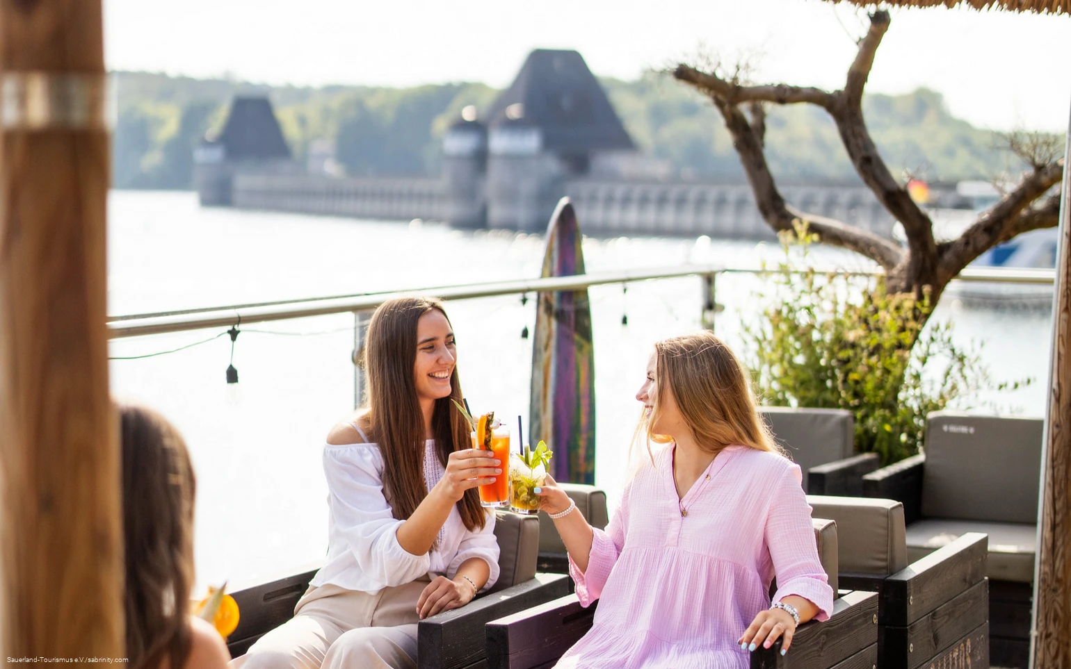 Zwei junge Frauen stoßen mit Cocktails im Restaurant vor der Staumauer an
