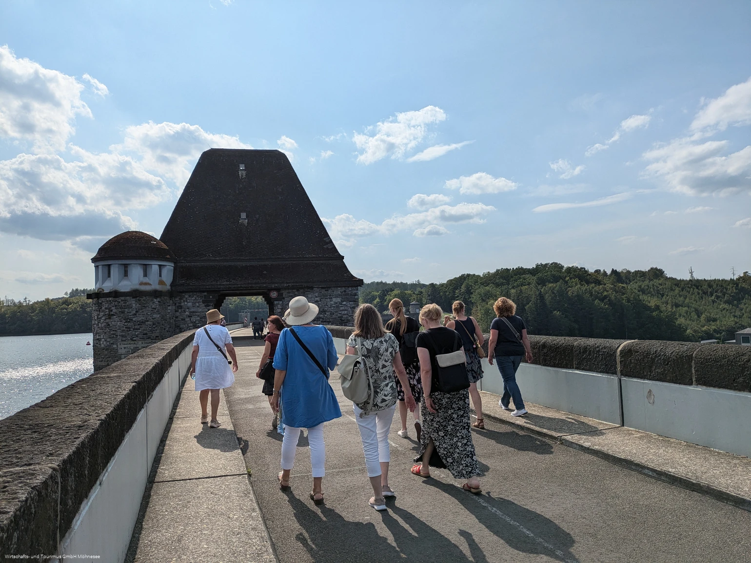 Gruppe von Personen spaziert über die Staumauer des Möhnesees.