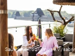Zwei junge Frauen stoßen mit Cocktails im Restaurant vor der Staumauer an